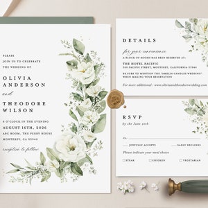 May include: A white wedding invitation with green foliage and white flowers. The invitation reads "Please join us to celebrate the wedding of Olivia Anderson and Theodore Wilson" and includes the date, time, and location of the wedding. The invitation also includes details for the hotel where a block of rooms has been reserved and an RSVP card.