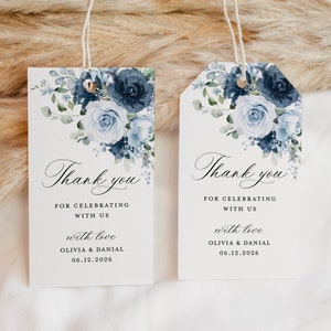 Puede incluir: Dos etiquetas de regalo de boda blancas con diseños florales azules en acuarela. El texto en las etiquetas dice "Gracias por celebrar con nosotros con amor Olivia & Danial 06.12.2026".