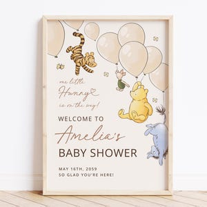 Pode incluir: Uma placa de ch&aacute; de beb&eacute; emoldurada com personagens de Winnie the Pooh e bal&otilde;es. A placa diz "Bem-vindo ao ch&aacute; de beb&eacute; de Amelia" com a data de 16 de maio de 2059. A arte inclui Tigr&atilde;o, Leit&atilde;o, Pooh e Eeyore.