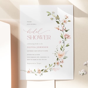 May include: A white bridal shower invitation with pink floral illustrations. The text reads "Please join us for a bridal shower celebrating bride-to-be Olivia Johnson, Saturday, May 16th at 3:00PM, Studio de la Flor, 2205 Faraday Ave, Carlsbad, CA, RSVP to name at 532.783.226, Registered at Target."