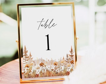 May include: A gold-framed table number sign with the text "Table 1" and a watercolor illustration of a forest scene with brown, orange, and yellow flowers.