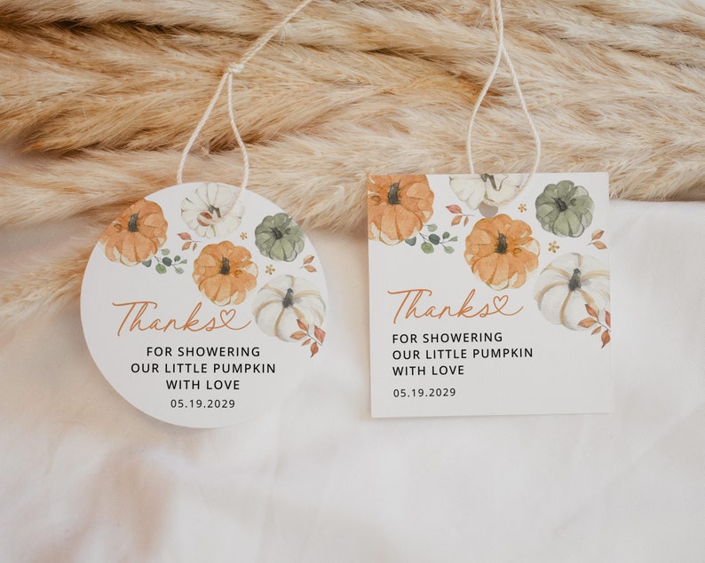 May include: Two round, white, thank you tags with a watercolor design of pumpkins, leaves, and flowers. The text on the tags reads "Thanks" with a heart symbol, "For showering our little pumpkin with love", and the date "05.19.2029".