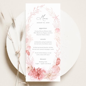 May include: A wedding menu card with a watercolor design featuring coral and seashells. The menu includes appetizers, entrées, and dessert options. The date August 25, 2059, is displayed at the top. The menu is on a white plate.