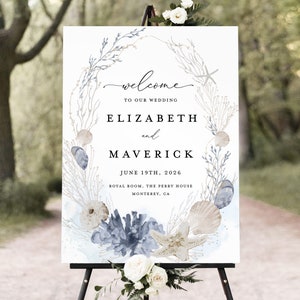 May include: A white wedding welcome sign with a watercolor illustration of seashells, starfish, and seaweed. The sign reads "Welcome to our wedding, Elizabeth and Maverick, June 19th, 2026, Royal Room, The Perry House, Monterey, CA."