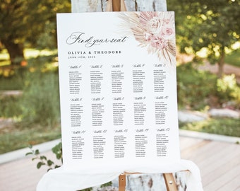 May include: A white wedding seating chart with a floral design in shades of pink and beige. The chart lists the names of guests assigned to each table. The text at the top reads "Find your seat Olivia & Theodore June 19th, 2023".