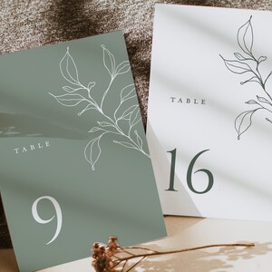 May include: Two table number cards with a minimalist design. The card on the left is green with white text and a white floral illustration. It reads "Table 9". The card on the right is white with black text and a black floral illustration. It reads "Table 16".