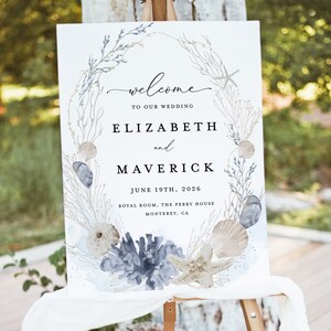 May include: A white wedding welcome sign with a watercolor illustration of seashells, starfish, and seaweed. The text reads "welcome to our wedding Elizabeth and Maverick June 19th, 2026 Royal Room, The Perry House Monterey, CA"
