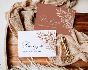 May include: Two thank you cards featuring a watercolour illustration of dried branches and flowers. The cards are displayed on a wooden surface with a brown fabric and a gold wax seal.