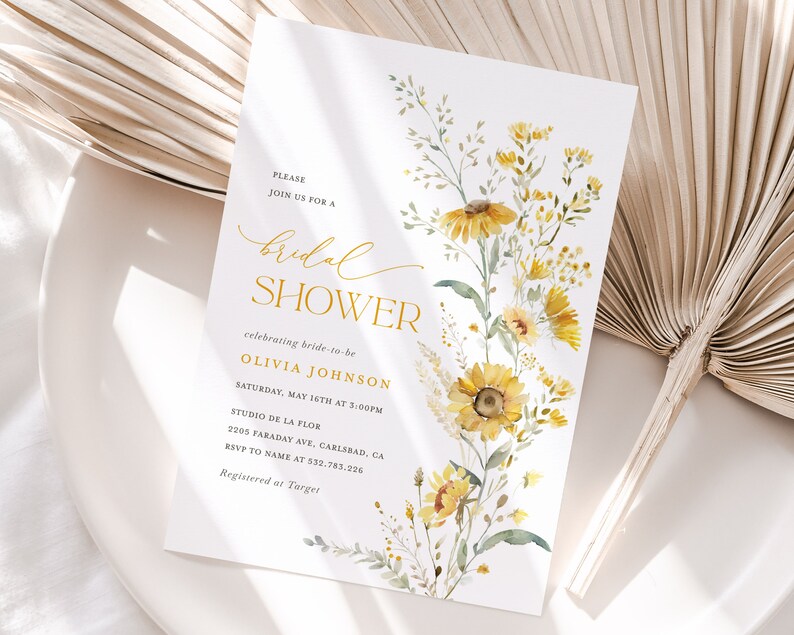 May include: A white bridal shower invitation with a watercolor illustration of yellow flowers and green leaves. The text reads "Please join us for a bridal shower celebrating bride-to-be Olivia Johnson Saturday, May 16th at 5:00PM Studio de la Flor 2205 Faraday Ave, Carlsbad, CA RSVP to name at 532.783.226 Registered at Target"