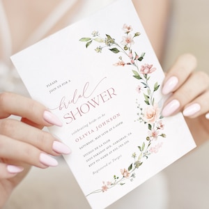 May include: A white bridal shower invitation with pink floral illustrations and the text "PLEASE JOIN US FOR A bridal SHOWER celebrating bride-to-be OLIVIA JOHNSON SATURDAY, MAY 16TH AT 3:00PM STUDIO DE LA FLOR 2205 FARADAY AVE, CARLSBAD, CA RSVP TO NAME AT 532.783.226 Registered at Target"