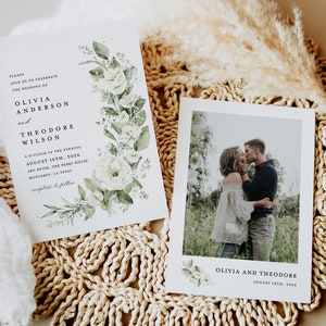 May include: A wedding invitation with white flowers and green leaves on a white background. The invitation reads "Please join us to celebrate the wedding of Olivia Anderson and Theodore Wilson 6 o'clock in the evening August 16th, 2026 ABC Room, The Perry House Monterey, CA 93940 reception to follow". A photo of the couple kissing is on a separate card with the text "Olivia and Theodore August 16th, 2026".