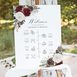 Pode incluir: Um cartaz de boas-vindas de casamento branco com um design floral bordô e branco. O cartaz lista a programação do dia do casamento com horários e ícones para cada evento. O texto diz "Bem-vindos ao nosso casamento Kathryn & Bradley".