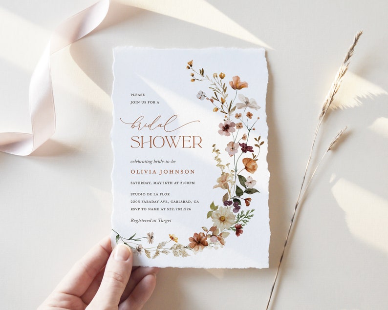 May include: A floral bridal shower invitation with a watercolor design of flowers in shades of pink, orange, and yellow. The text reads "Please join us for a bridal shower celebrating bride-to-be Olivia Johnson Saturday, May 16th at 5:00PM Studio de la Flor 2205 Faraday Ave, Carlsbad, CA RSVP to name at 532.783.226 Registered at Target"