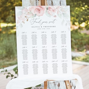 以下が含まれることがあります： ピンクのバラと緑の葉が描かれた花柄の白い結婚式席次表。各テーブルに割り当てられたゲストの名前がリストされており、上部には「Find your seat」と「Olivia & Theodore」の文字が書かれています。