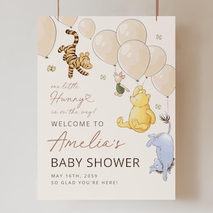 Pode incluir: Um letreiro de ch&aacute; de beb&eacute; com ilustra&ccedil;&otilde;es de personagens de Winnie the Pooh, bal&otilde;es e borboletas. O letreiro diz "our little Hunny is on the way! Welcome to Amelia's Baby Shower" com a data de 16 de maio de 2059.