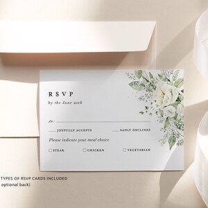 May include: White RSVP card with a floral design in the top right corner. The card has the text "RSVP by the June 20th" and includes options for guests to indicate if they will be joyfully accepting, sadly declining, or their meal choice: steak, chicken, or vegetarian.