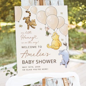 Pode incluir: Uma placa de ch&aacute; de beb&ecirc; com personagens de Winnie the Pooh e bal&otilde;es. A placa diz: "our little Hunny is on the way! Welcome to Amelia's Baby Shower May 16th, 2059, So glad you're here!" A placa est&aacute; em um cavalete.