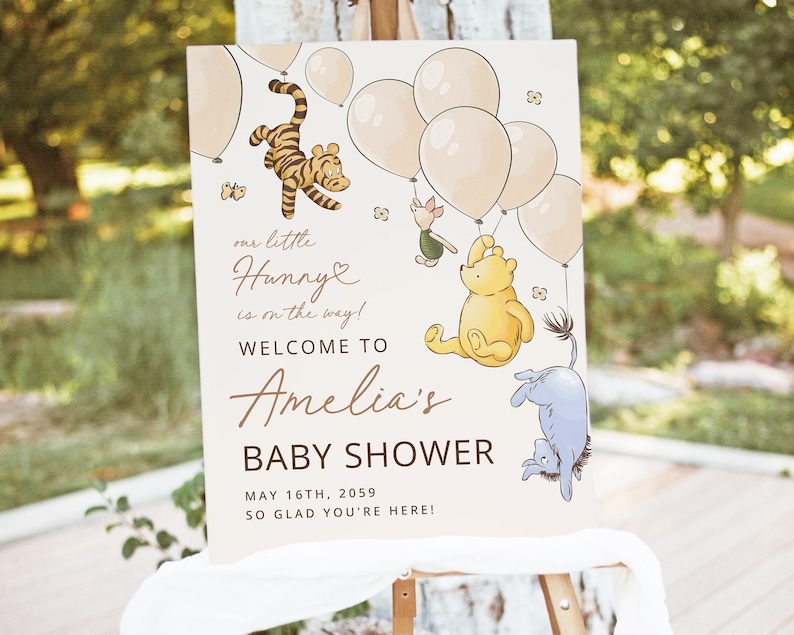 Pode incluir: Uma placa de ch&aacute; de beb&ecirc; com personagens de Winnie the Pooh e bal&otilde;es. A placa diz: "our little Hunny is on the way! Welcome to Amelia's Baby Shower May 16th, 2059, So glad you're here!" A placa est&aacute; em um cavalete.