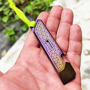 May include: A multi-colored metal keychain with a geometric pattern and a bottle opener. The keychain is attached to a green lanyard.