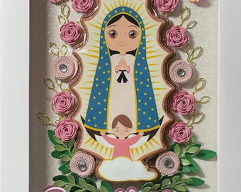 May include: A framed image of Our Lady of Guadalupe with pink paper flowers and butterflies surrounding the image. The name "Rosa Maria" is written in pink letters at the bottom of the frame.