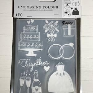 May include: A clear plastic embossing folder with a wedding theme. The folder features a cake, rings, a bouquet, a champagne bottle and glasses, a dress, and the word "Together".