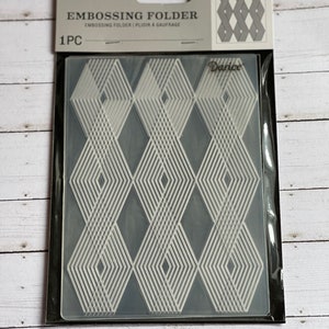 May include: A clear plastic embossing folder with a geometric diamond pattern. The folder is packaged in a clear plastic sleeve with a white label that reads "Embossing Folder" and "Darice".