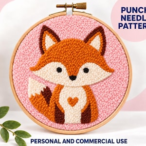 以下が含まれることがあります： 木製の刺繍枠に入ったパンチニードル作品。ピンクの背景にオレンジ、白、ダークブラウンの糸で描かれたキツネが特徴です。PUNCH NEEDLE PATTERN, PERSONAL AND COMMERCIAL USE, YOU CAN MAKE AND SELL KITSというテキストが表示されています。