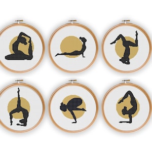 May include: Six embroidery hoops with a white background and a gold circle in the center. Each hoop features a black silhouette of a person in a different yoga pose.