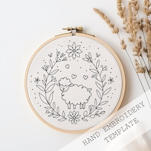 May include: Black and white embroidery template featuring a cute sheep surrounded by a floral wreath. The template is displayed in a wooden embroidery hoop. Hand Embroidery Template.
