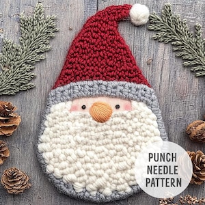 Puede incluir: Un patrón de aguja de punzón para un adorno de Papá Noel. El patrón presenta un gorro de crochet rojo, una barba blanca y una cara gris con ojos negros y una nariz naranja. El texto "PUNCH NEEDLE PATTERN" es visible en la esquina inferior derecha de la imagen.