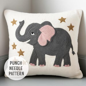 May include: Cream-colored square throw pillow featuring a gray elephant with pink ears and feet, surrounded by gold stars. The pillow has a textured, hand-stitched appearance. The text "PUNCH NEEDLE PATTERN" is in a white circle in the lower left corner.