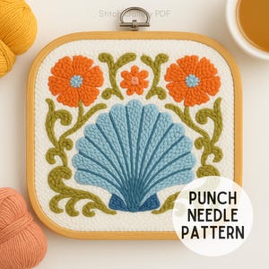 Könnte beinhalten: Quadratisches Stanznadelmuster in einem Holzrahmen. Das Design zeigt eine blaue Muschel, orangefarbene Blumen und grüne Ranken auf weißem Hintergrund. Der Text "PUNCH NEEDLE PATTERN" befindet sich in einem weißen Kreis.