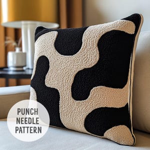 May include: A black and cream throw pillow with a punch needle design of abstract shapes. The pillow is on a cream colored couch. "Punch Needle Pattern" is written in black text on a white circle.
