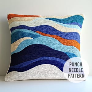 May include: Square decorative pillow with a textured punch needle pattern. The design features layered wave-like patterns in shades of blue, orange, and cream against a white background. The pillow has a white border and the text "PUNCH NEEDLE PATTERN" is visible.