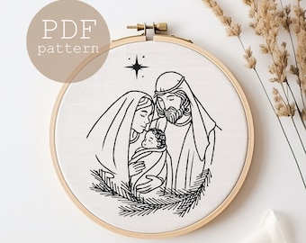 May include: Black and white line drawing of the Holy Family, Mary, Joseph, and baby Jesus, with a star above them. The image is on a white background and is framed in a wooden hoop.