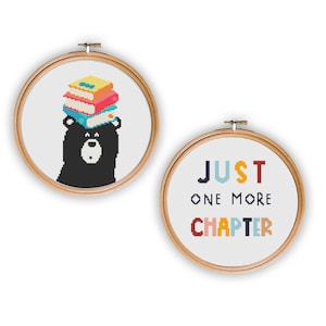 May include: Two embroidery hoops with cross-stitch designs. The first hoop features a black bear with a stack of colorful books on its head. The second hoop has the text "JUST ONE MORE CHAPTER" in colorful letters.