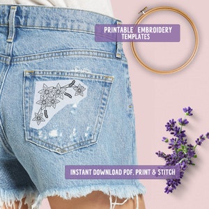 May include: Light blue denim shorts with a floral embroidery design on the back pocket. The image includes text that reads "PRINTABLE EMBROIDERY TEMPLATES" and "INSTANT DOWNLOAD PDF, PRINT & STITCH". An embroidery hoop and lavender sprig are also visible.