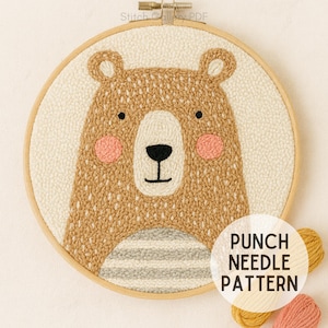 Puede incluir: Un patrón de aguja mágica con un diseño de oso amigable. El oso tiene pelaje marrón, mejillas rosadas y una nariz y ojos negros. El diseño está en un aro de bordado de madera con el texto "PUNCH NEEDLE PATTERN".