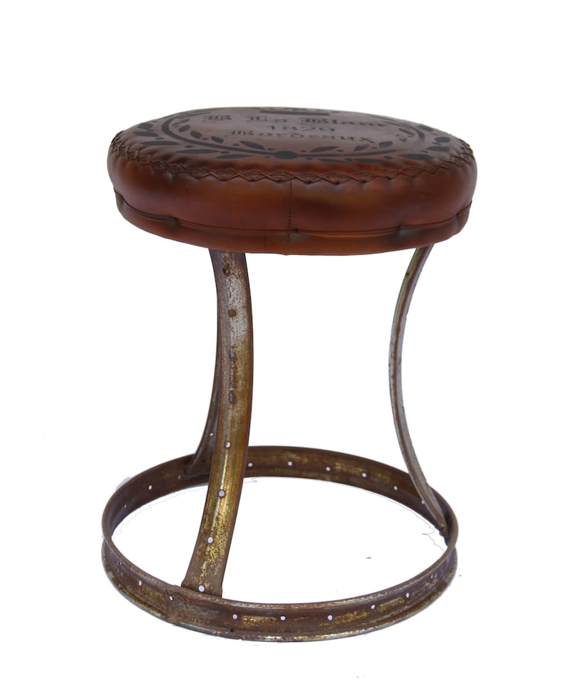 Puede incluir: Un taburete de cuero marr&oacute;n con un asiento circular y una base de metal. El asiento tiene un dise&ntilde;o decorativo y el texto "X.O. Special Reserve 1927 Bordeaux" impreso en &eacute;l.