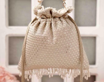 May include: A champagne-coloured drawstring pouch bag featuring an all-over sequin pattern, a beaded top handle, and a beaded fringe along the bottom edge. The bag includes two side drawstrings finished with pearl-accented tassels for closure.