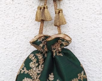 以下が含まれることがあります： 複雑な金色のメタリックな花柄刺繍が施されたダークグリーンの巾着袋。バッグの上部は金色の紐で絞られており、それぞれの紐の先にはビーズのアクセントと金属糸のディテールがあしらわれた装飾的なタッセルが付いています。