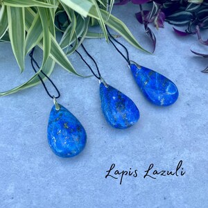 以下が含まれることがあります： 黒い紐に、涙滴型のラピスラズリペンダントが3つ。ペンダントは深い青色で、金色の斑点がある。ペンダントの下には、筆記体で「Lapis Lazuli」と書かれている。