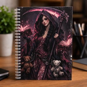 May include: Spiral-bound notebook with a fantasy illustration of a robed figure holding a scythe and books, with two teddy bears. The colour palette is dominated by shades of red, black, and purple. The notebook is on a wooden surface.
