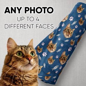 K&ouml;nnte beinhalten: Eine blaue Fleece-Decke mit einem sich wiederholenden Muster aus rosa Pfotenabdr&uuml;cken, wei&szlig;en Fischgr&auml;ten und Katzenk&ouml;pfen. Der Text "ANY PHOTO UP TO 4 DIFFERENT FACES" befindet sich oben im Bild.