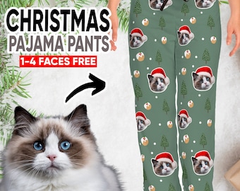 May include: Green pajama pants with a Christmas-themed pattern featuring multiple images of cats wearing Santa hats. The text "CHRISTMAS PAJAMA PANTS 1-4 FACES FREE" is displayed above the image.