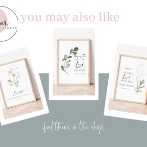 May include: Three framed art prints with inspirational quotes and botanical illustrations. The prints are in light wood frames and feature phrases like "Be Still" and "Trust in the Lord." The overall aesthetic is minimalist and calming.
