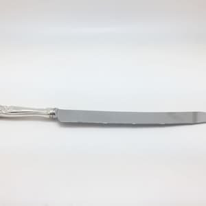 May include: A silver cake knife with an ornate handle and a serrated blade.