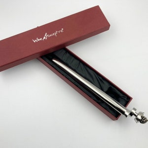May include: A silver wine bottle stopper with a decorative grape cluster design. The stopper is in a red box with the words "Wine Sceptre" printed on the top.