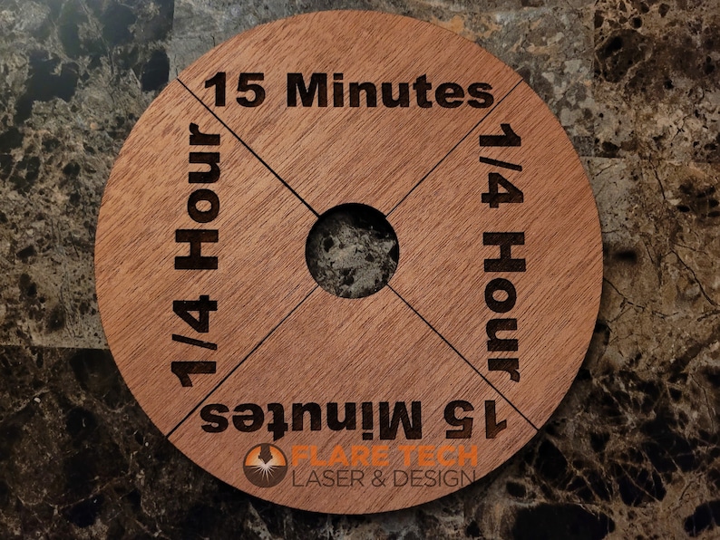 Peut inclure: Un minuteur en bois avec quatre sections, chacune marqu&eacute;e d'un incr&eacute;ment de temps diff&eacute;rent : 15 minutes, 1/4 heure, 15 minutes et 1/4 heure. Le minuteur est fabriqu&eacute; par Flare Tech Laser & Design.