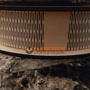 Peut inclure: Gros plan d'un cercle en bois avec un motif g&eacute;om&eacute;trique d&eacute;coup&eacute;. Le cercle est sur une surface brune. Le texte "FLARE TECH LASER & DESIGN" est visible sur le cercle.